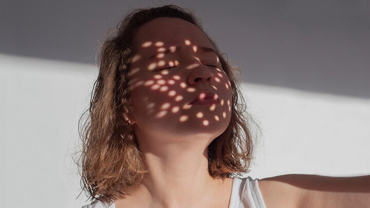 Light spots pay on a womans face as conceptual pimples